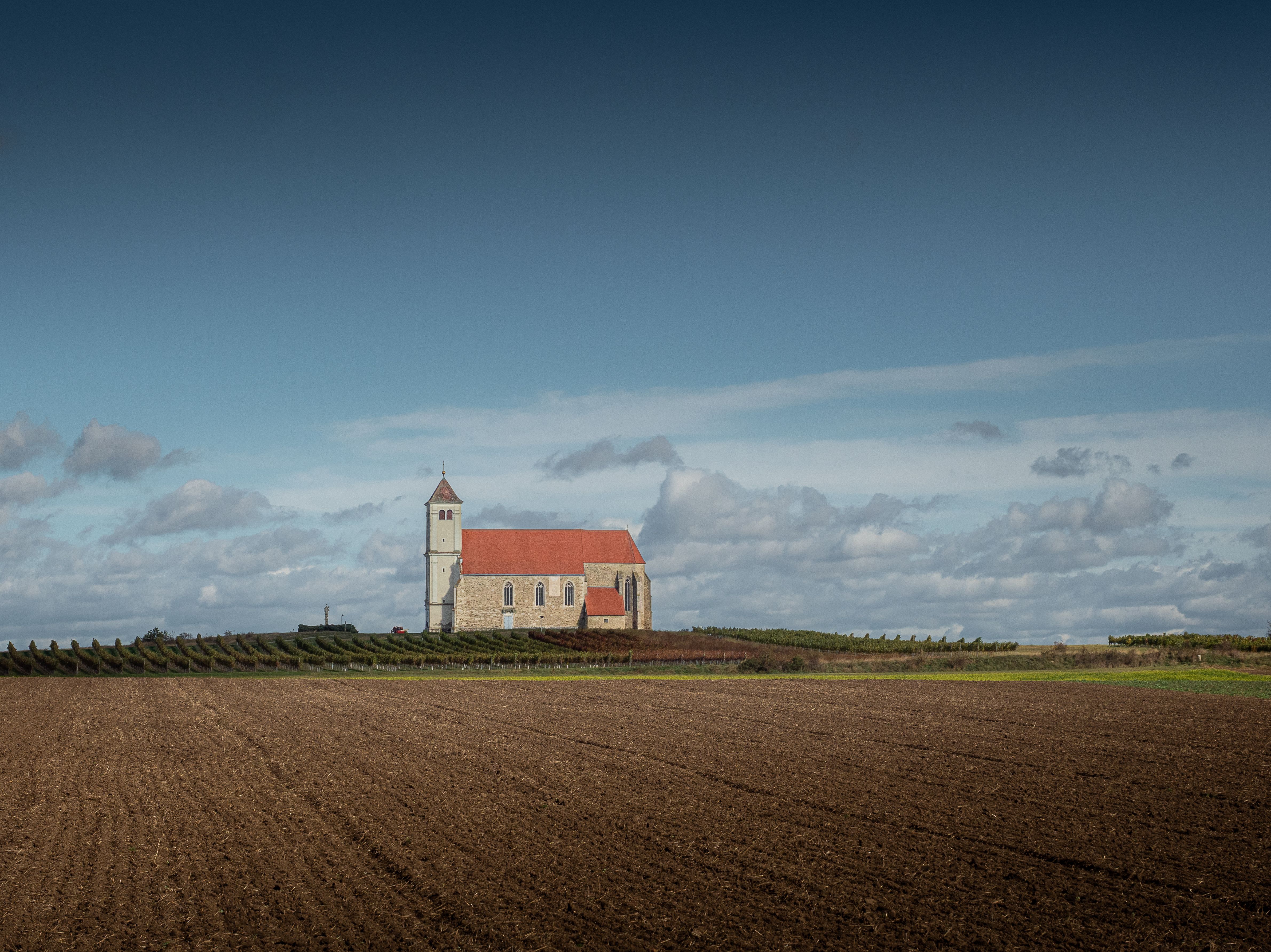 A person walking away from a traditional church building into a foggy, open field
