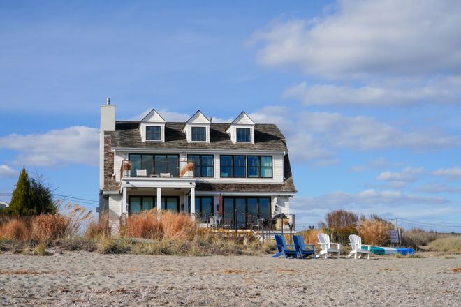 Beachfront house with patio chairs among dune grasses — photo by Cara Denison on Pexels
