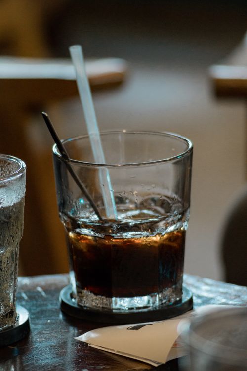 Free A refreshing close-up of an iced drink in a glass with two straws on a table. Stock Photo