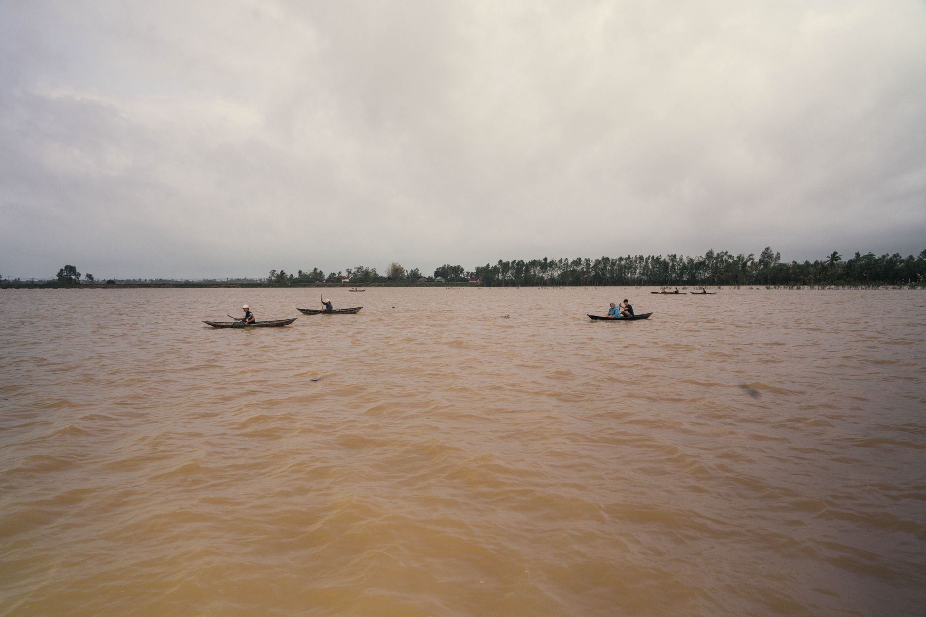 Peaceful view of small boats floating on a river under cloudy skies in Phú Yên, Vietnam.