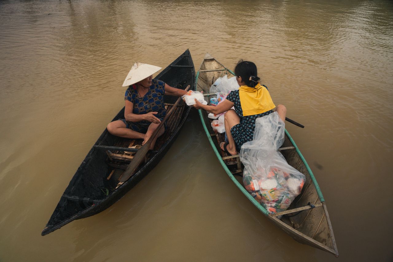 two people on boats exchanging goods on a river in ph y n vietnam