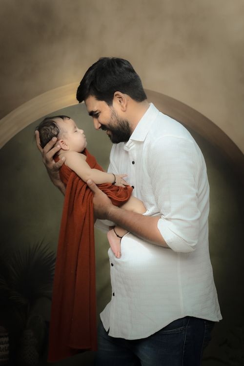 Free Heartwarming studio portrait of a father cradling his newborn baby in a loving pose. Stock Photo