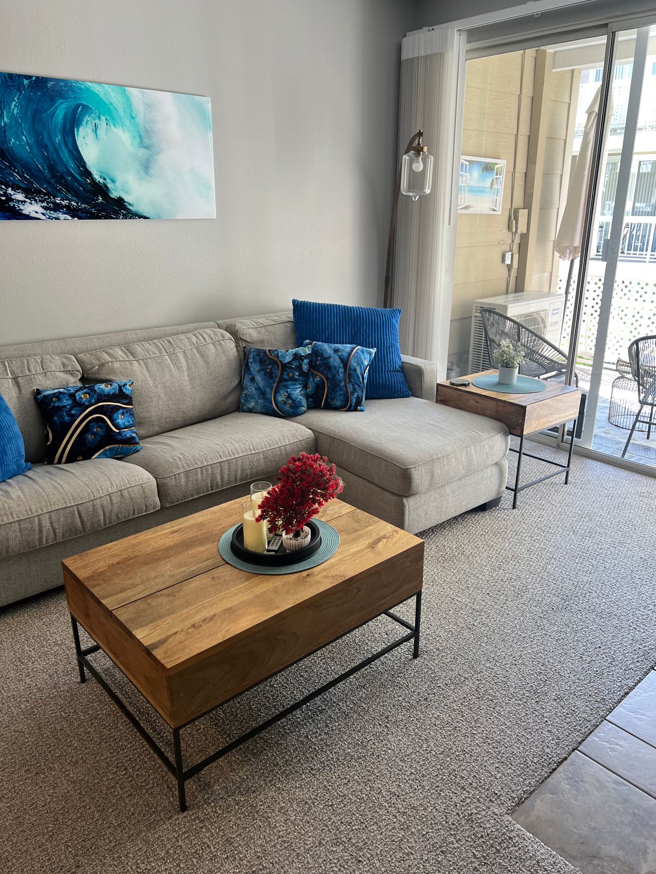 Gray sectional sofa with blue ocean-themed throw pillows and a large wave painting