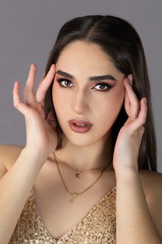 Close-up portrait of a woman with glamorous makeup and sparkling dress, exuding elegance.