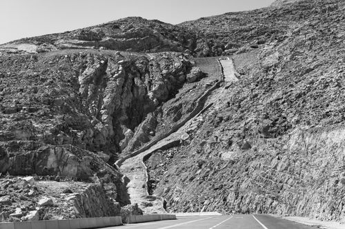 Free Black and white photograph of a winding road through a rugged mountain landscape. Stock Photo
