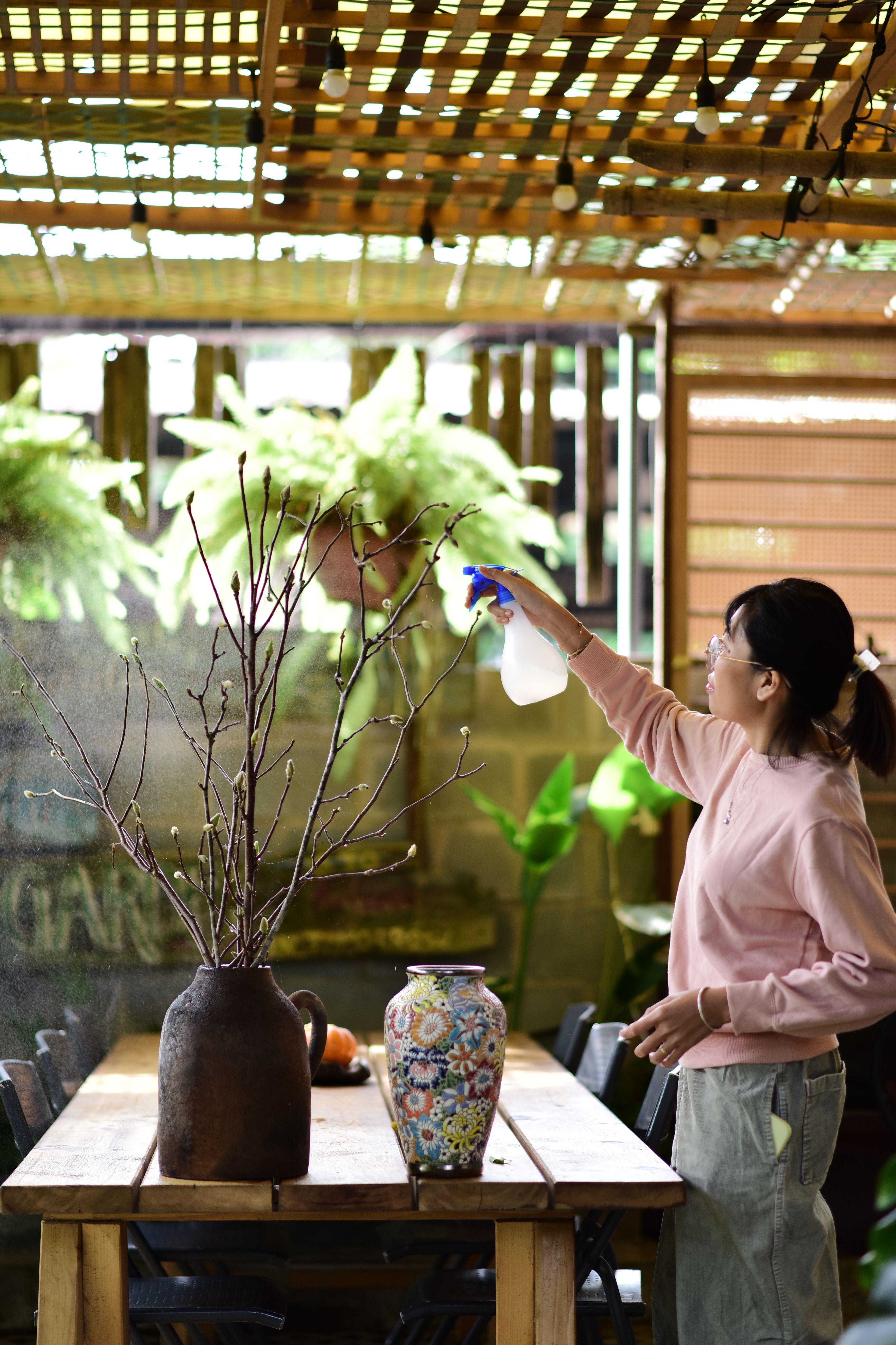 Frutíferas em vaso: mulher cuidando de plantas em vasos sobre mesa de madeira em um pátio