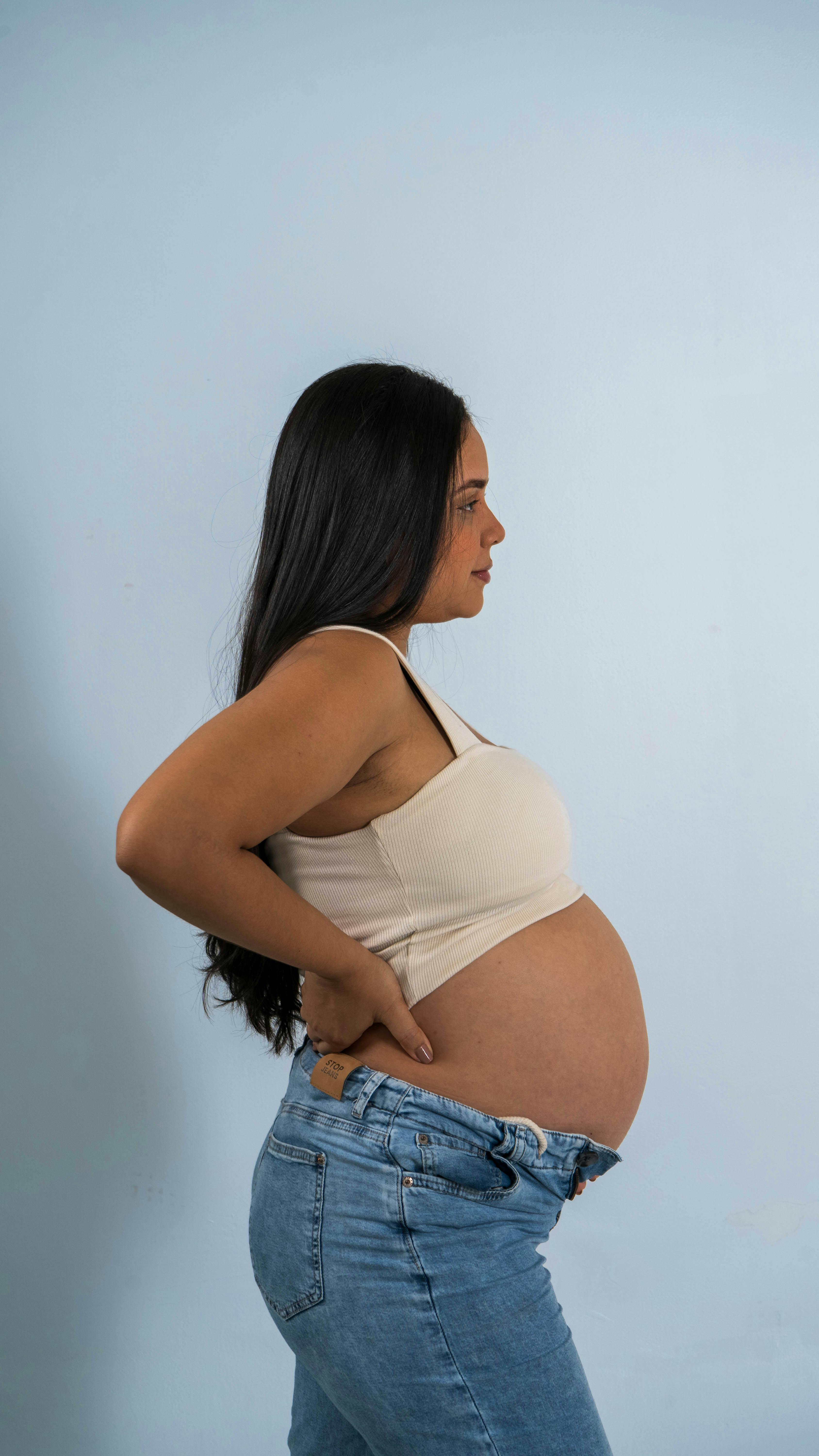 Profile view of a pregnant woman indoors, highlighting maternity and expecting motherhood.