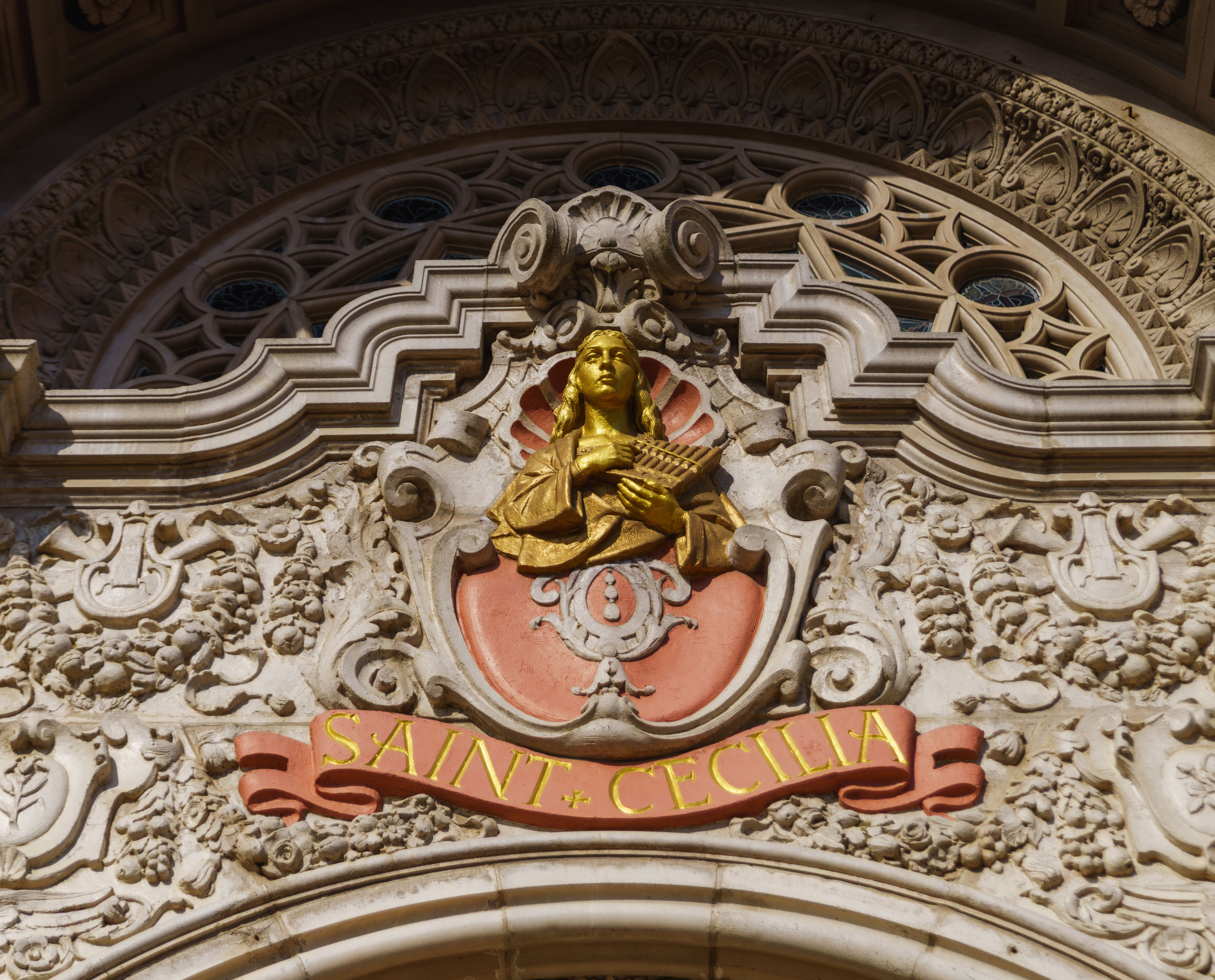 Ornate facade of Saint Cecilia church displaying intricate carvings and gold detailing.