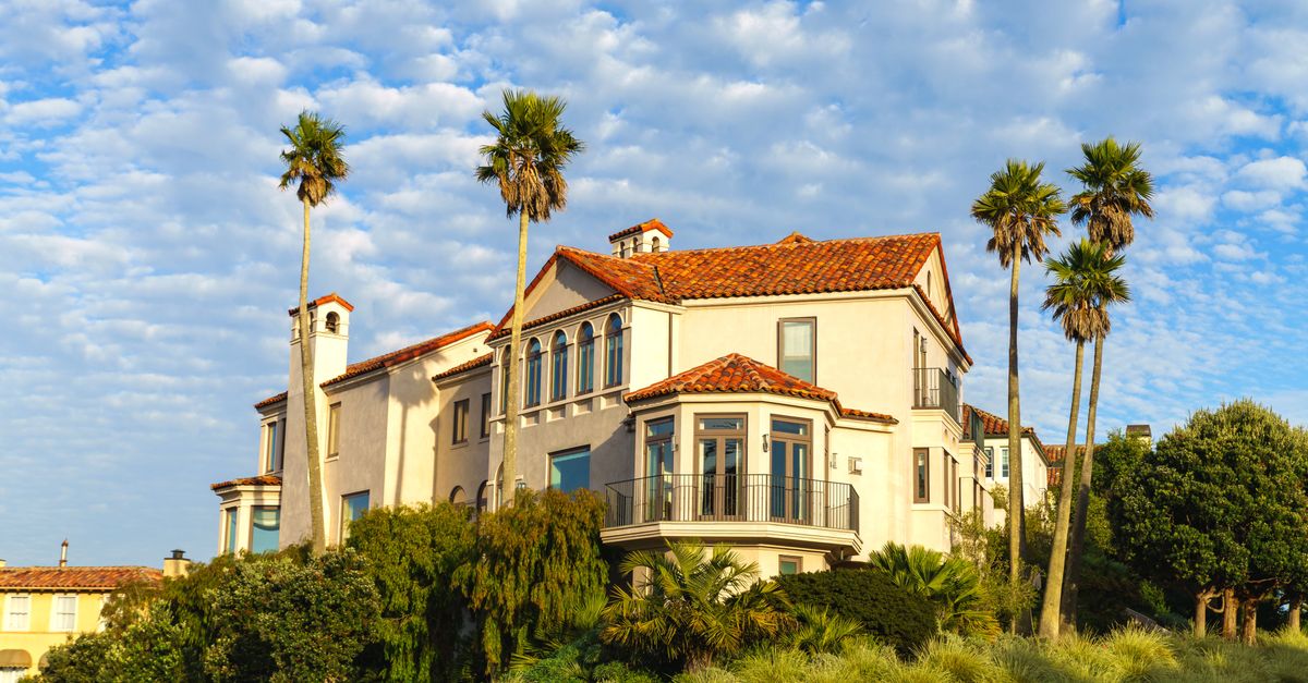Elegant Mediterranean villa surrounded by palm trees under a bright blue sky.