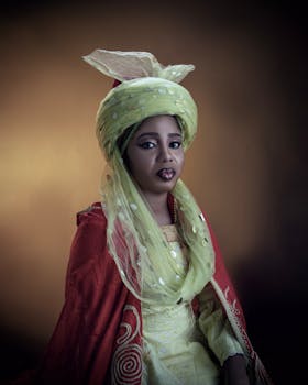 Woman in vibrant traditional dress, posed elegantly against a warm background.