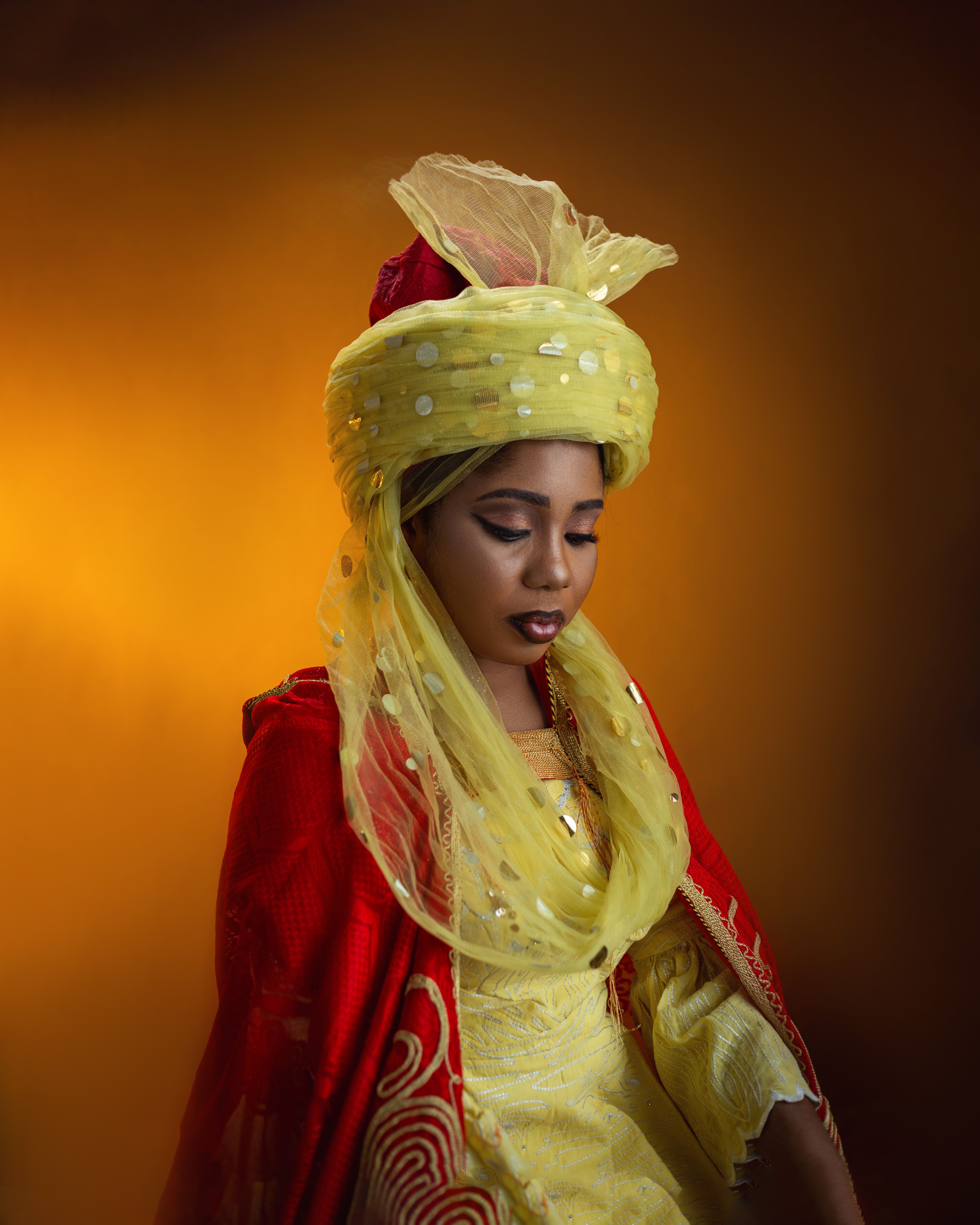Beautiful woman in vibrant traditional dress with expressive lighting on warm background.