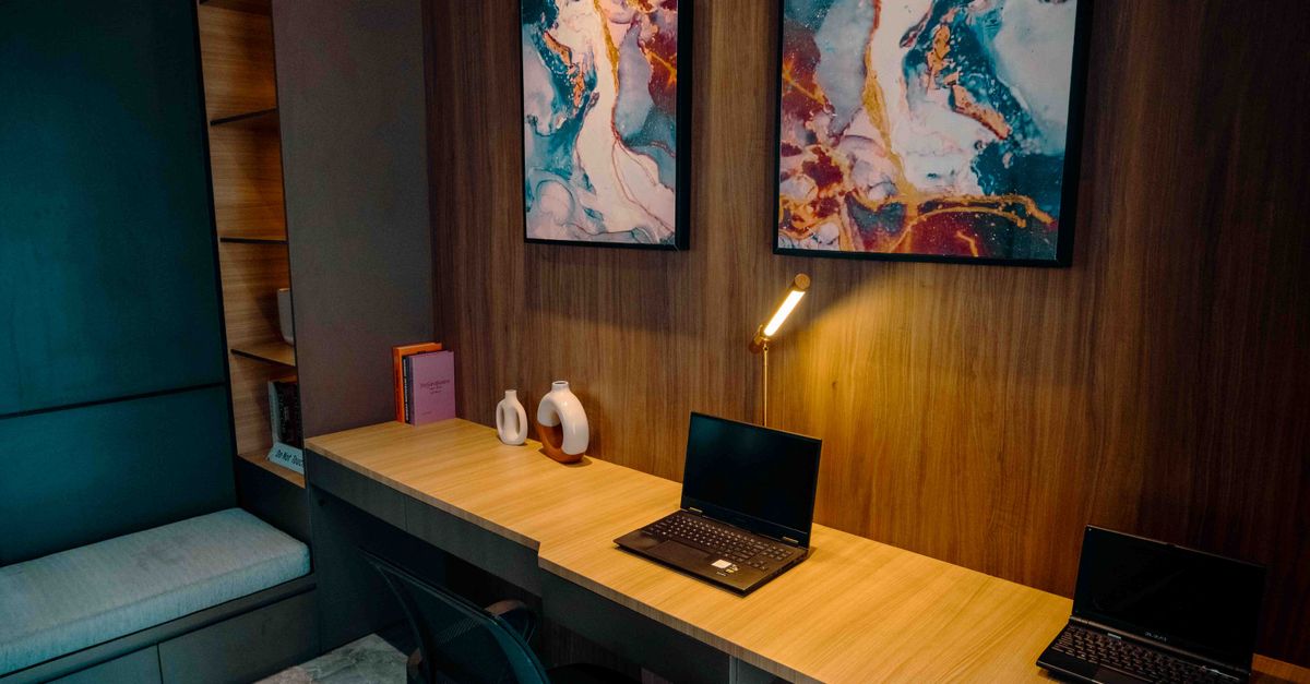 Cozy office workspace in Jakarta with abstract art, laptops, and ambient lighting.