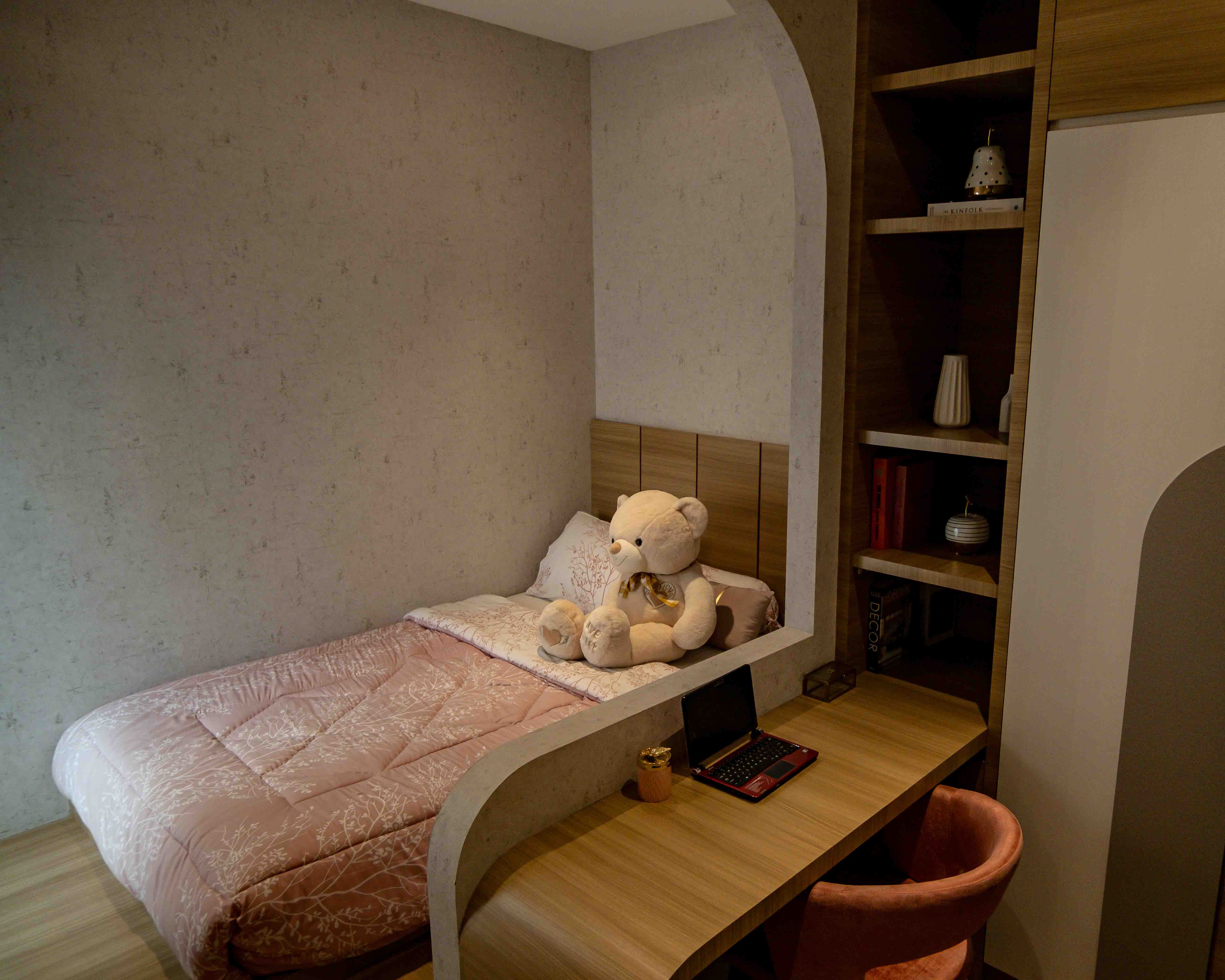 Elegant bedroom design in Jakarta featuring a cozy bed, desk, and plush teddy bear.