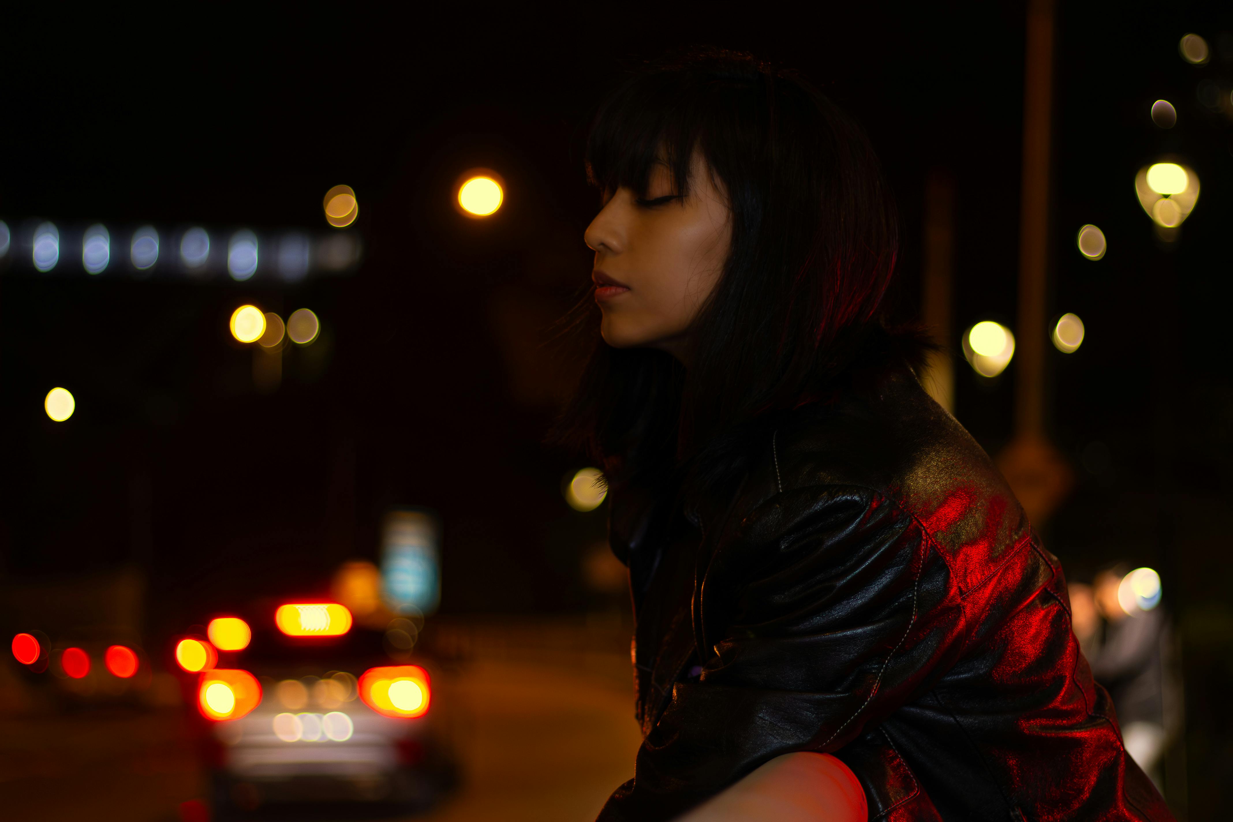 Stylish woman in leather jacket with bokeh lights at night in Miraflores, Lima.