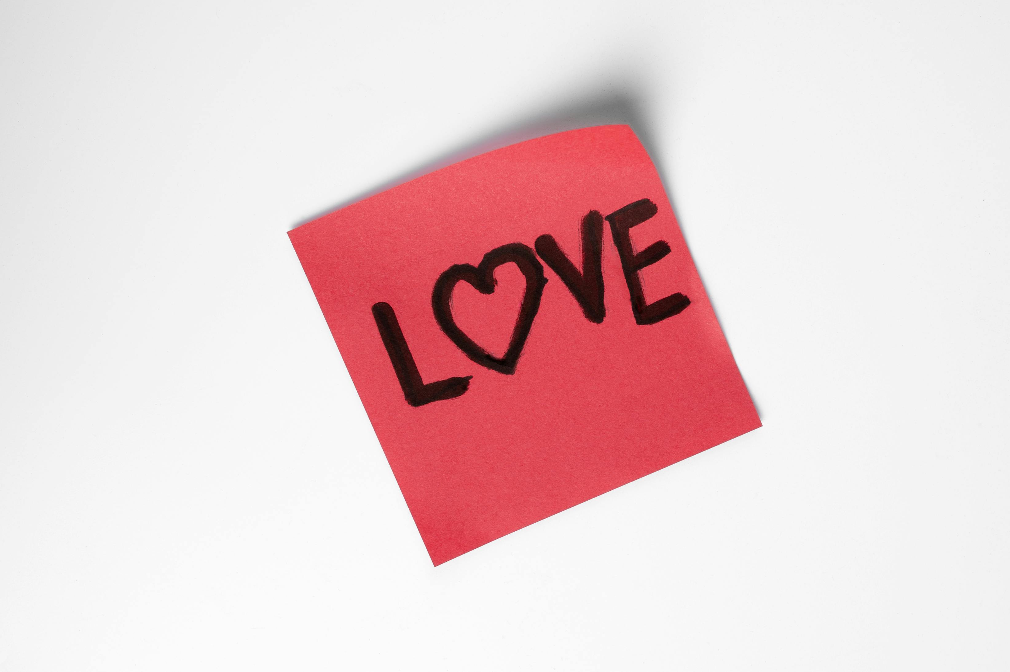 Free A red sticky note with love written in black ink, featuring a heart. Stock Photo