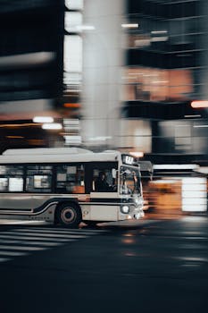 Dynamic nighttime photo of a moving bus in Kyoto showcasing urban life and motion blur.