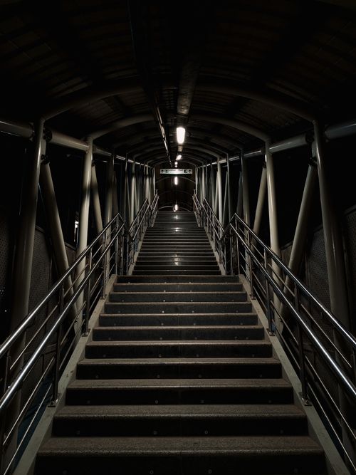 Free A dramatic shot of a dimly lit covered staircase at night with industrial design. Stock Photo