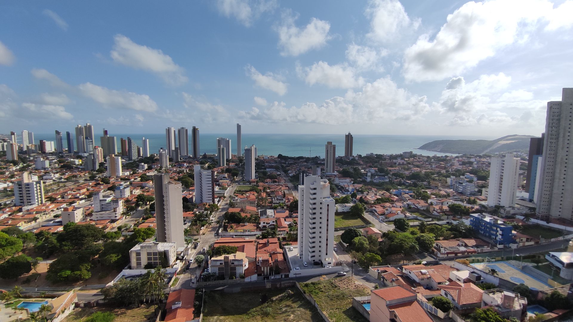 Aerial view of Natal, Brazil showcasing the skyline and Ponta Negra Beach under a sunny sky.