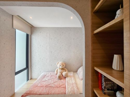 Free A modern bedroom with a large teddy bear on a pink bedspread, viewed through an archway. Stock Photo