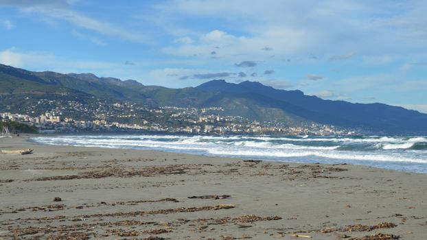 A scenic view of the beach in Bastia, Corse, France with mountains in the background.