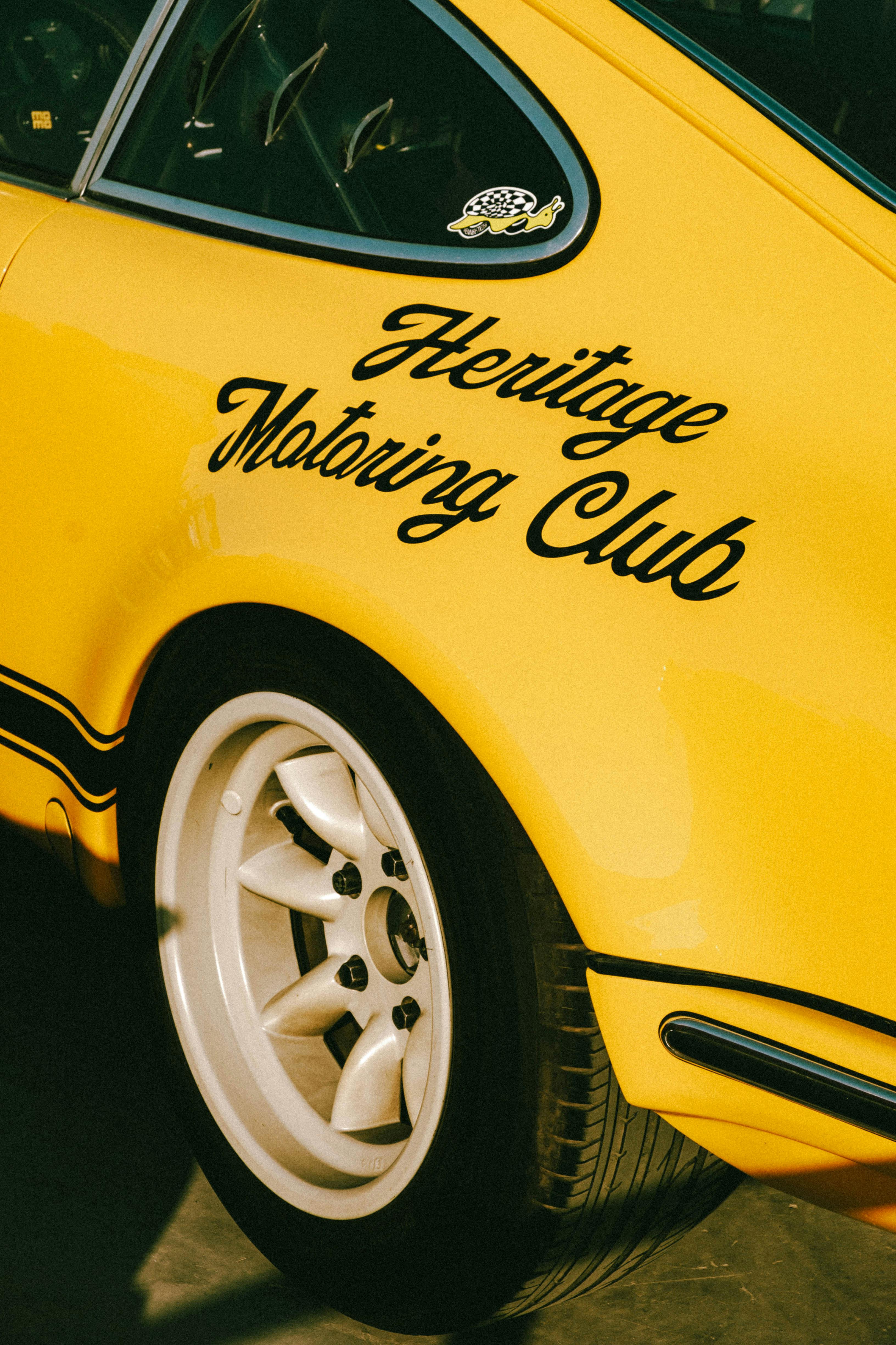 Close-up of a yellow vintage car with 'Heritage Motoring Club' text, capturing classic car aesthetics in Dubai.