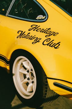 Close-up of a yellow vintage car with 'Heritage Motoring Club' text, capturing classic car aesthetics in Dubai.