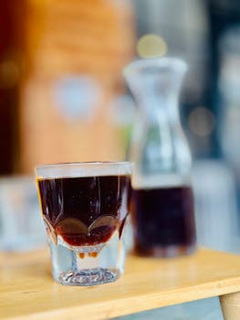 Freshly brewed coffee in a glass with carafe on a wooden table, Nusa Tenggara Barat, Indonesia.