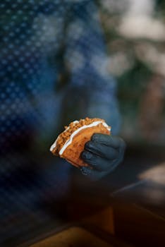 Close-up of a person holding a delicious taco with a black gloved hand, blurred background.