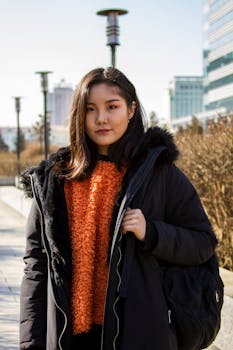 冬天，公园里一位穿着黑色夹克、背着背包的年轻女子正向前看