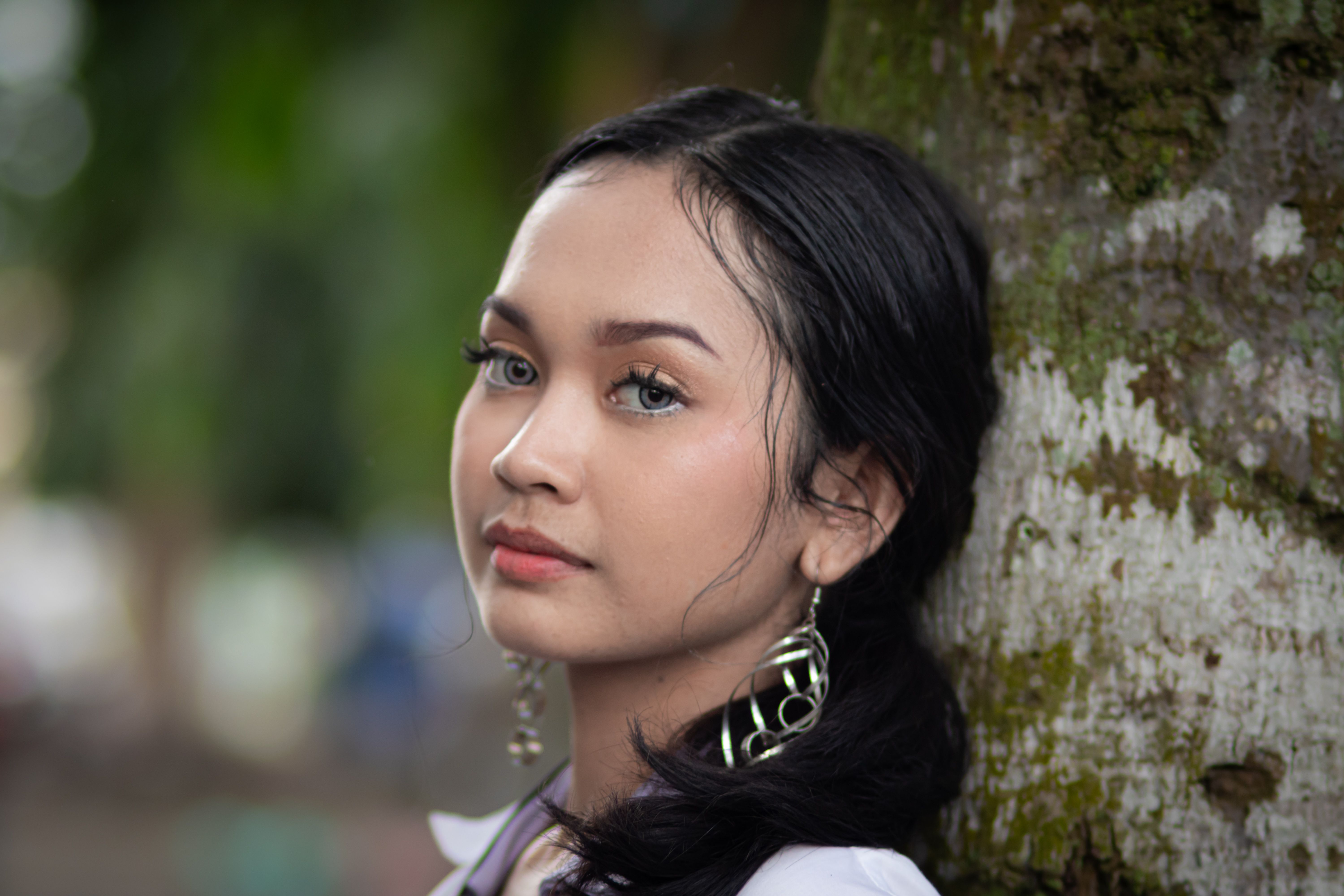 Close-up portrait of a young woman with earrings outdoors.