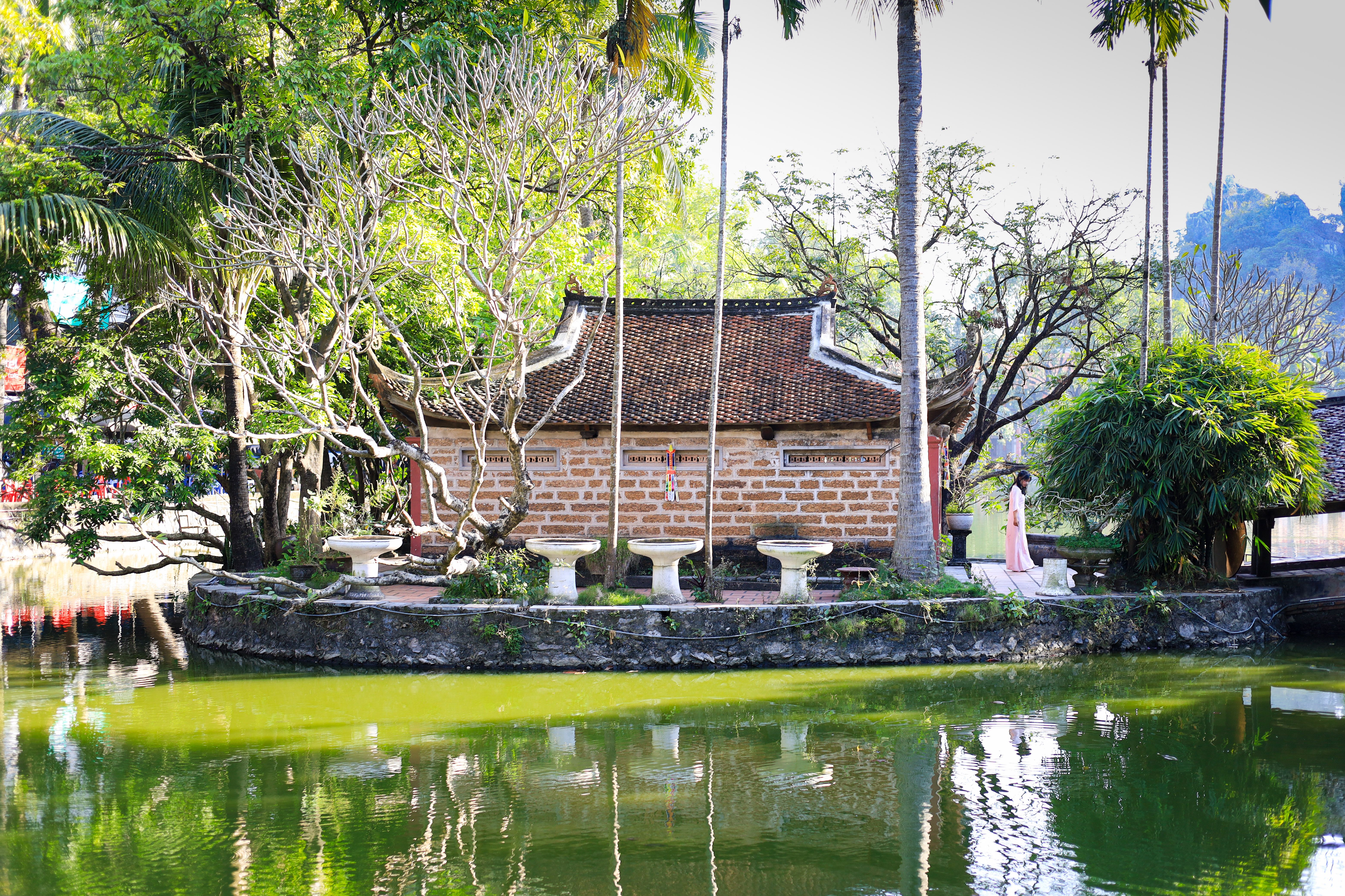 Traditional Vietnamese pagoda in lush surroundings with a serene pond reflection, located in Hanoi.