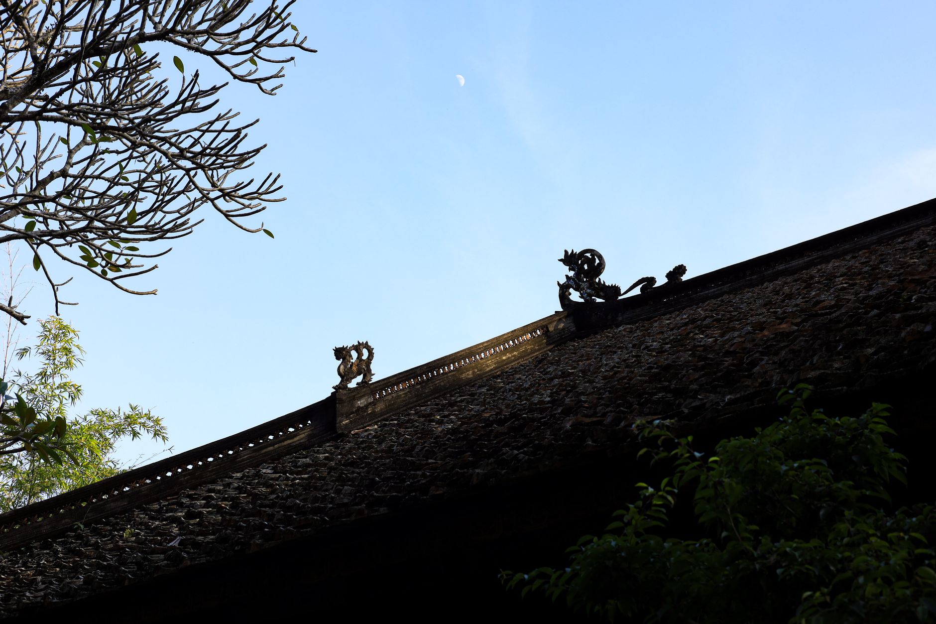 Close-up of a traditional Vietnamese roof with ornate designs against a clear sky in Hanoi.