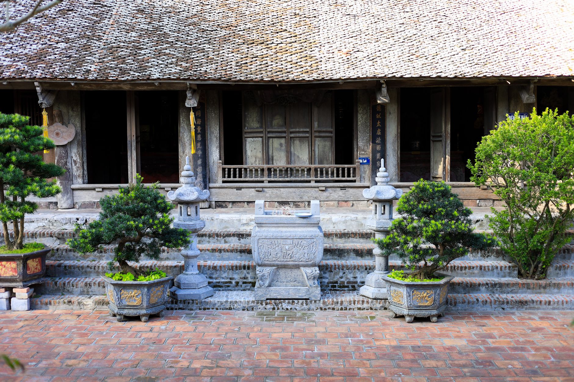 An ancient temple facade with plants in Hanoi, Vietnam showcasing traditional architecture.