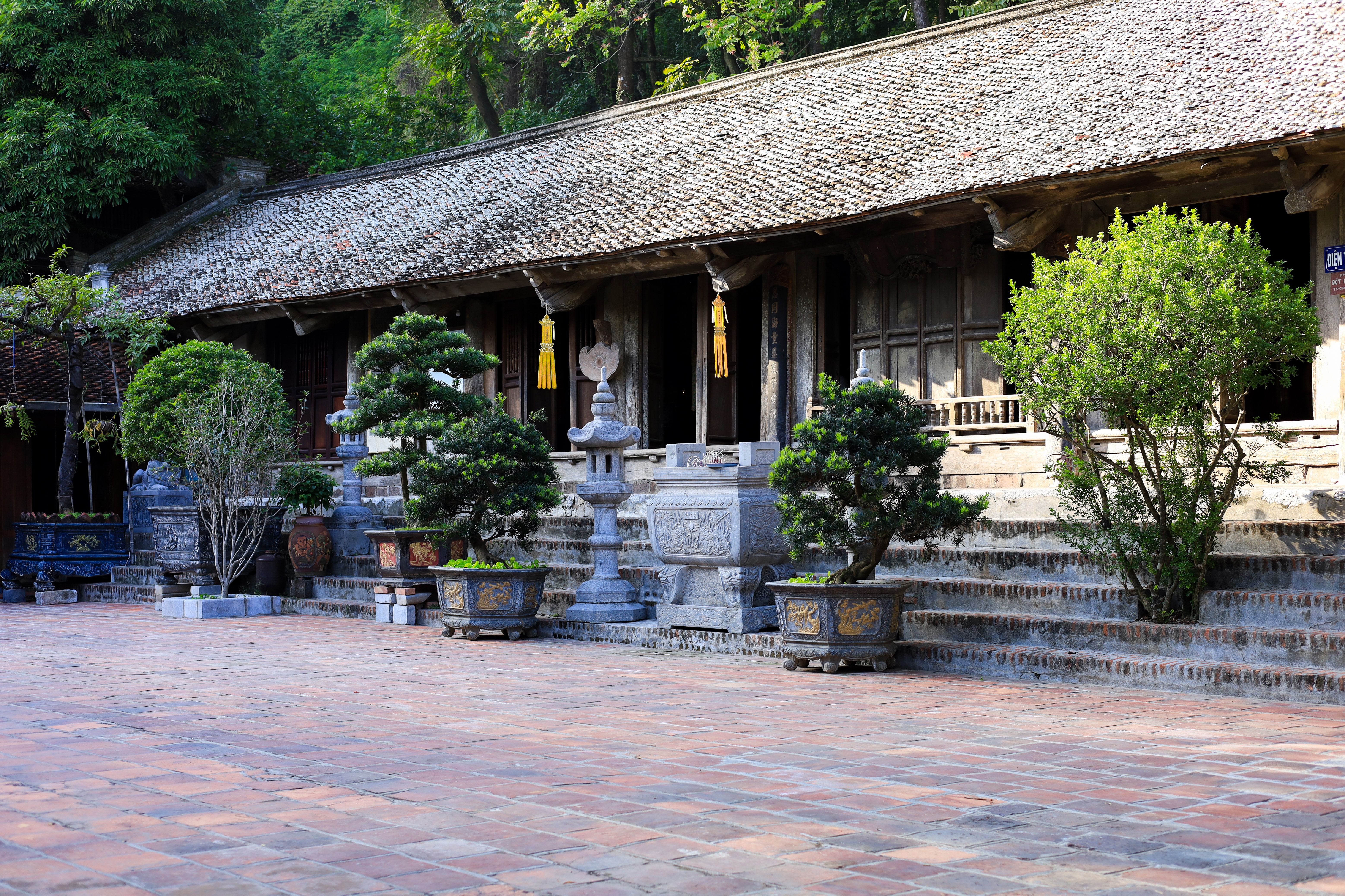 Historic temple courtyard in Hanoi, showcasing Vietnamese architecture and lush greenery.