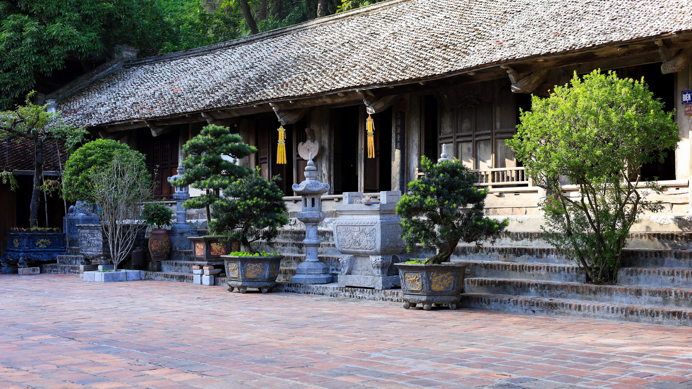 Historic temple courtyard in Hanoi, showcasing Vietnamese architecture and lush greenery.