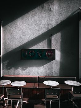 Modern cafe interior with neon love sign casting shadows, creating a moody atmosphere.