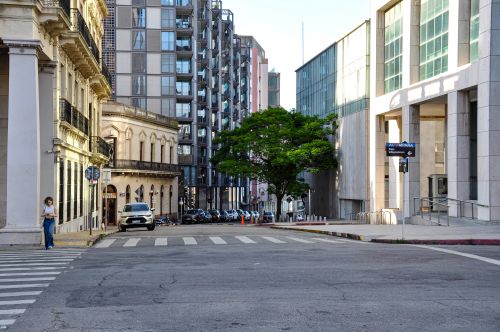 Free Street view of Montevideo with modern and historic architecture, featuring a lone pedestrian. Stock Photo