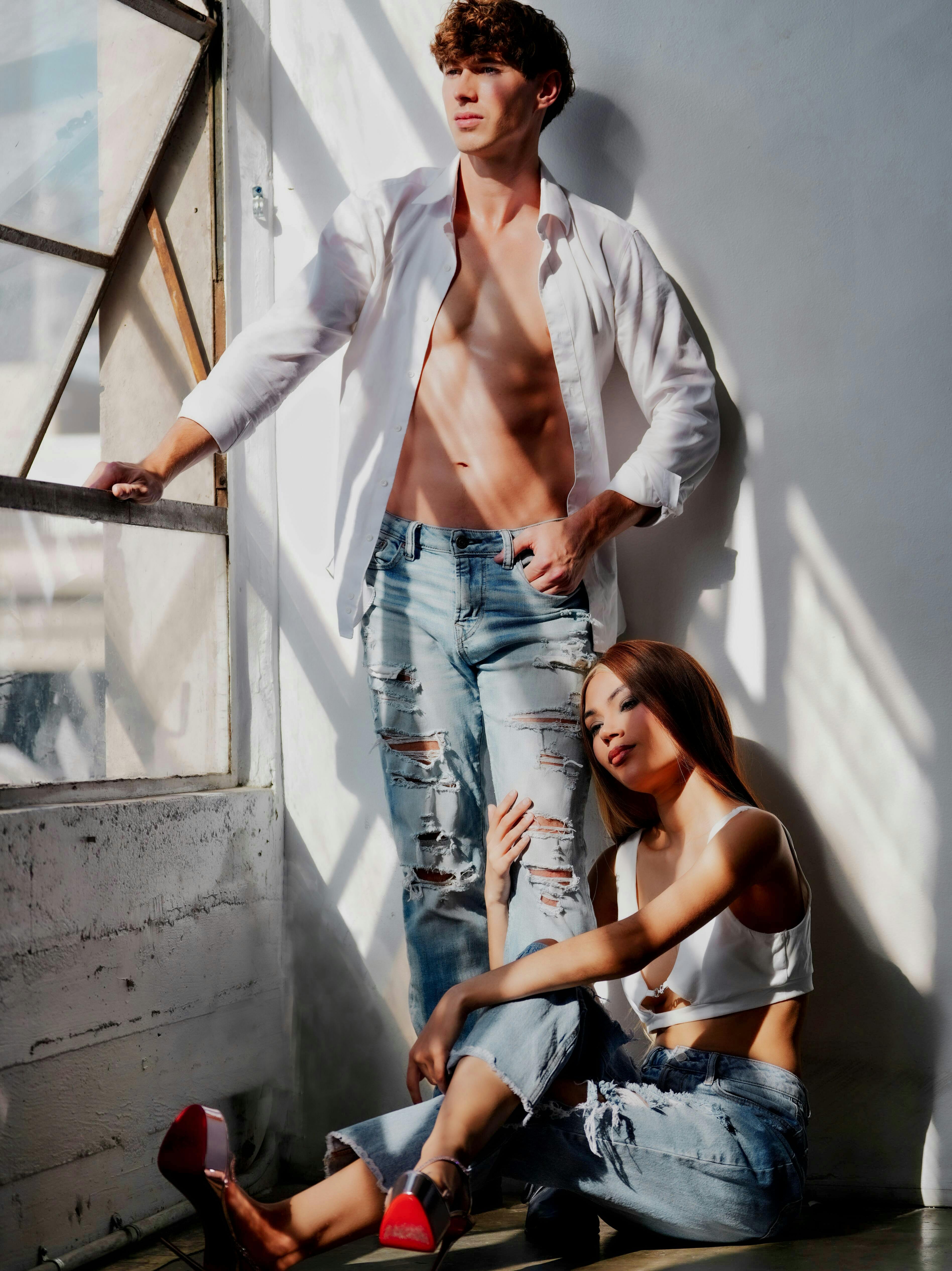 Couple relaxing intimately by window with soft natural light, evoking deep connection and sensual calm before deeper surrender