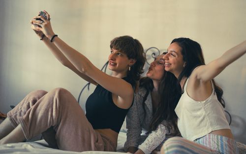 Free Three young women enjoying a casual selfie moment together indoors. Stock Photo