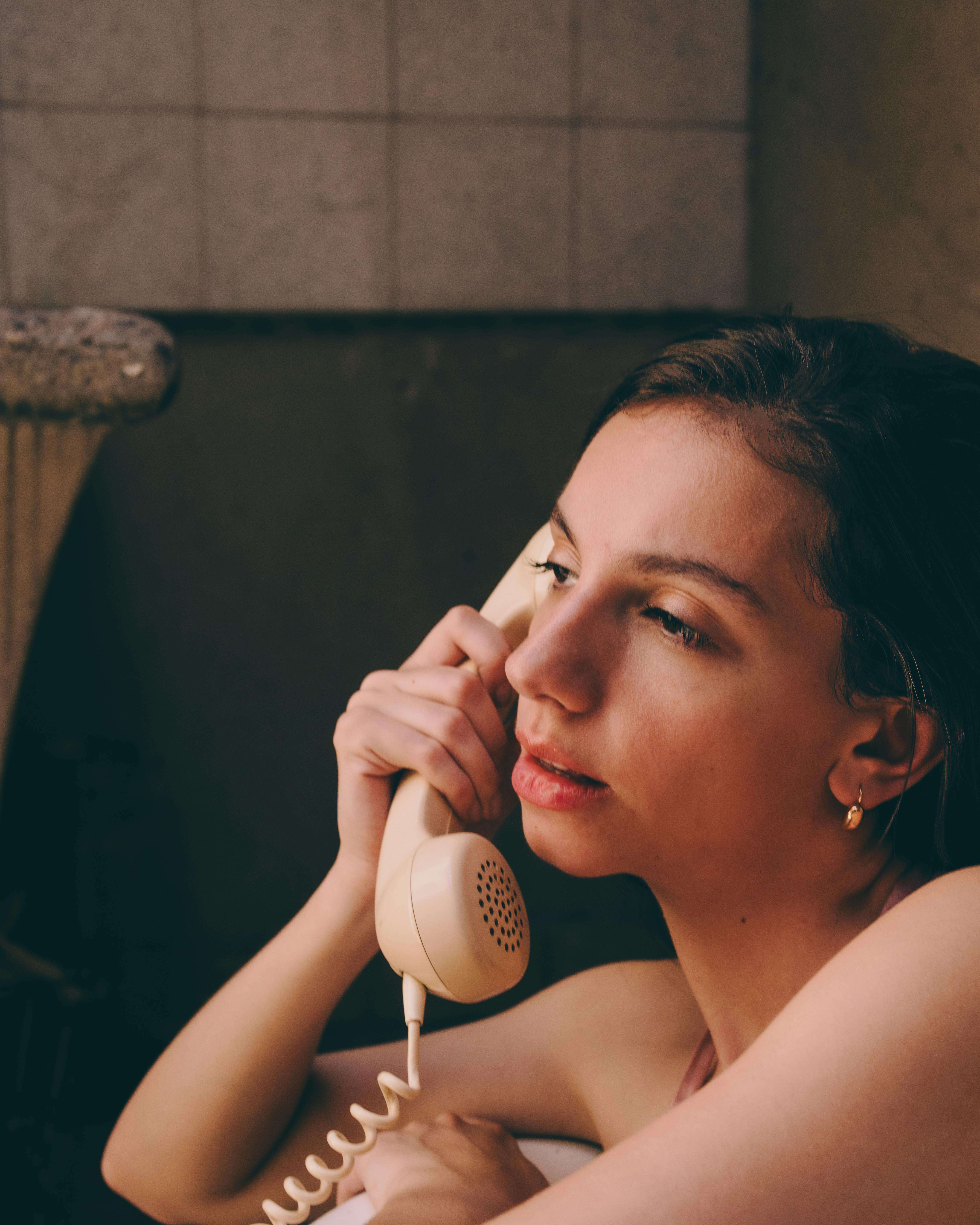 Kostenlos Eine Frau in einem nostalgischen Ambiente benutzt ein kabelgebundenes Telefon und verströmt damit Nostalgie. Stock-Foto