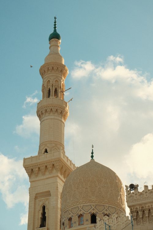 Free A beautiful view of a mosque's minaret and dome against a clear sky, showcasing intricate Islamic architecture. Stock Photo