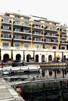 Elegant hotel by marina with docked yacht reflecting luxury travel.