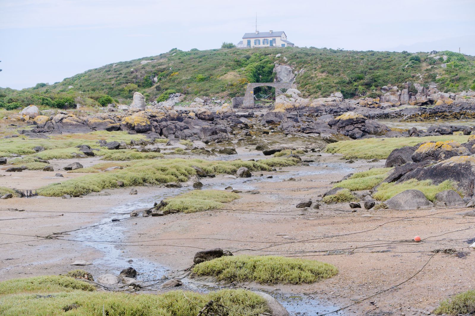 Estran à marée basse sous une maison de pierre et une arche à Chausey