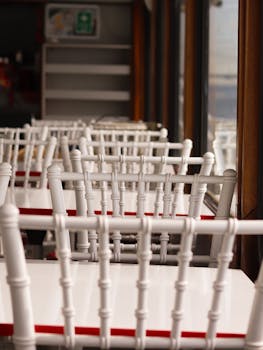 Bright and airy empty restaurant with white chairs lined up, creating a serene atmosphere.