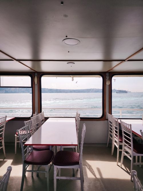Free Peaceful boat interior with tables and chairs, overlooking the sea through large windows. Stock Photo