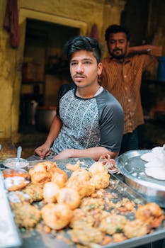 Young man serves traditional Indian street food in Varanasi market.