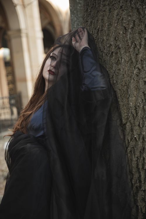 Free Mysterious woman with black veil in a gothic atmosphere against a tree outdoors. Stock Photo