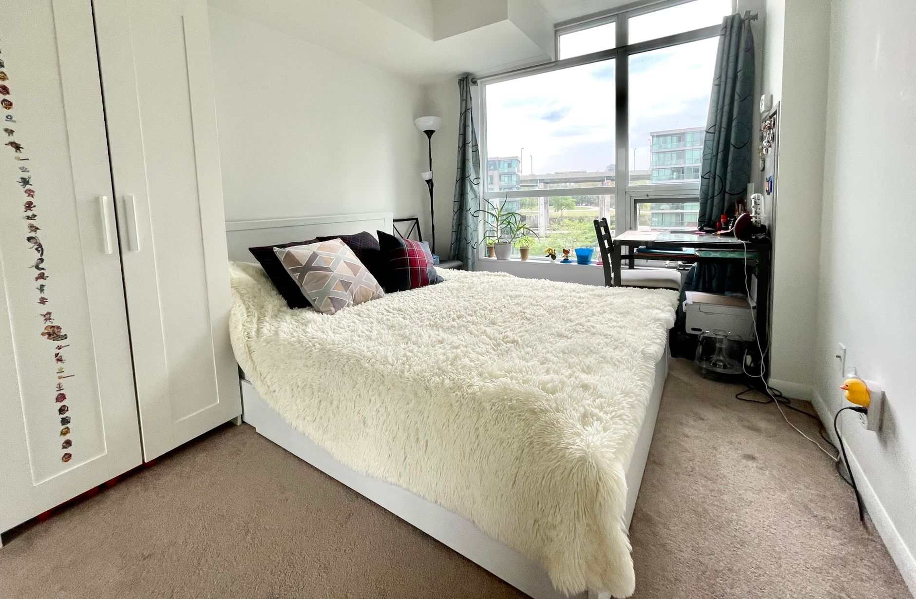 A cozy and modern bedroom with a large window view in Toronto, Ontario.