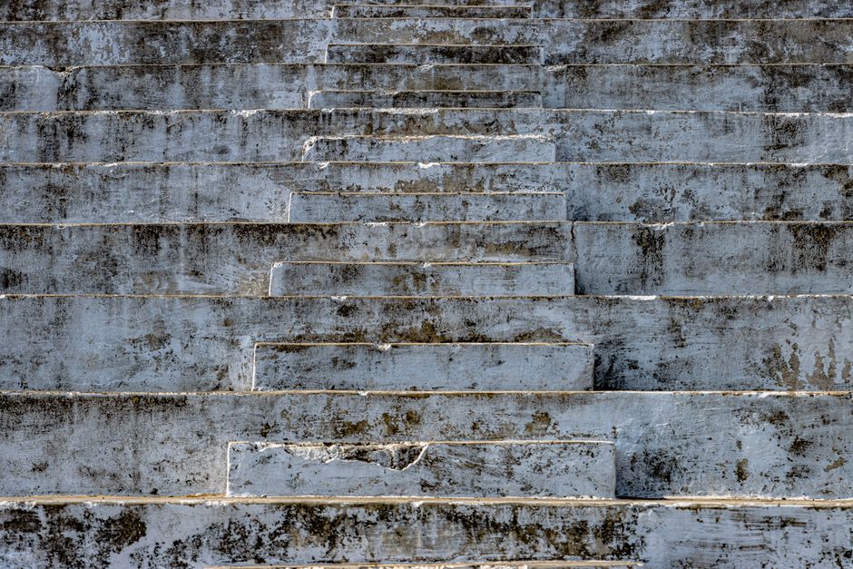 Textured, weathered concrete steps in an abandoned stadium in Hazaribagh, India, showcasing brutalist architecture.