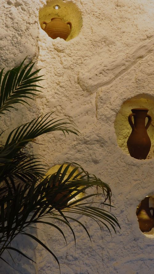 Free Rustic clay pots in a textured wall niche with surrounding green foliage. Stock Photo